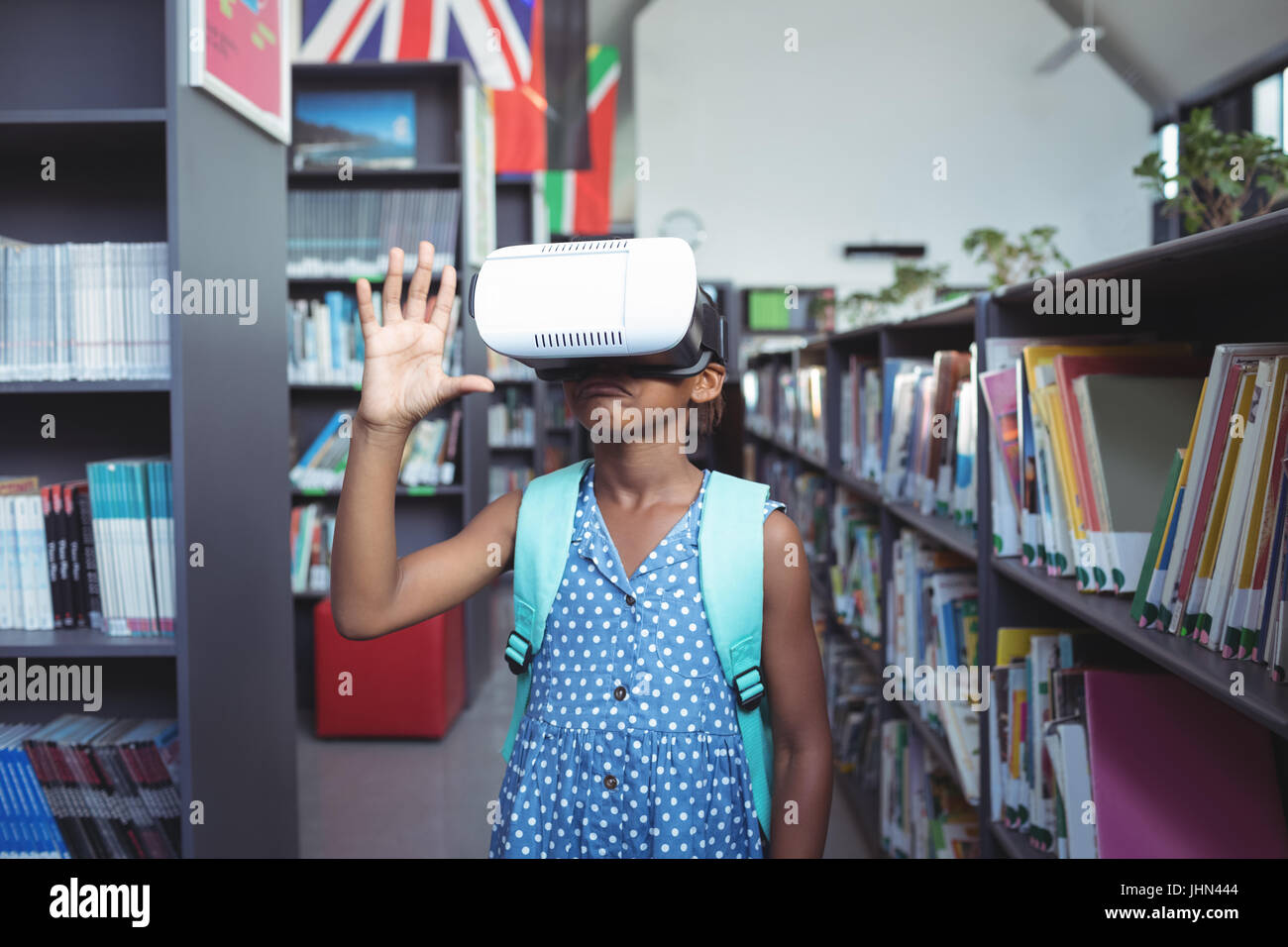 Girl gesturing while wearing virtual reality simulator in library Stock ...