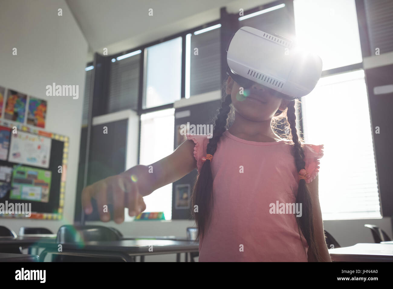 Girl gesturing while wearing virtual reality simulator in school Stock ...