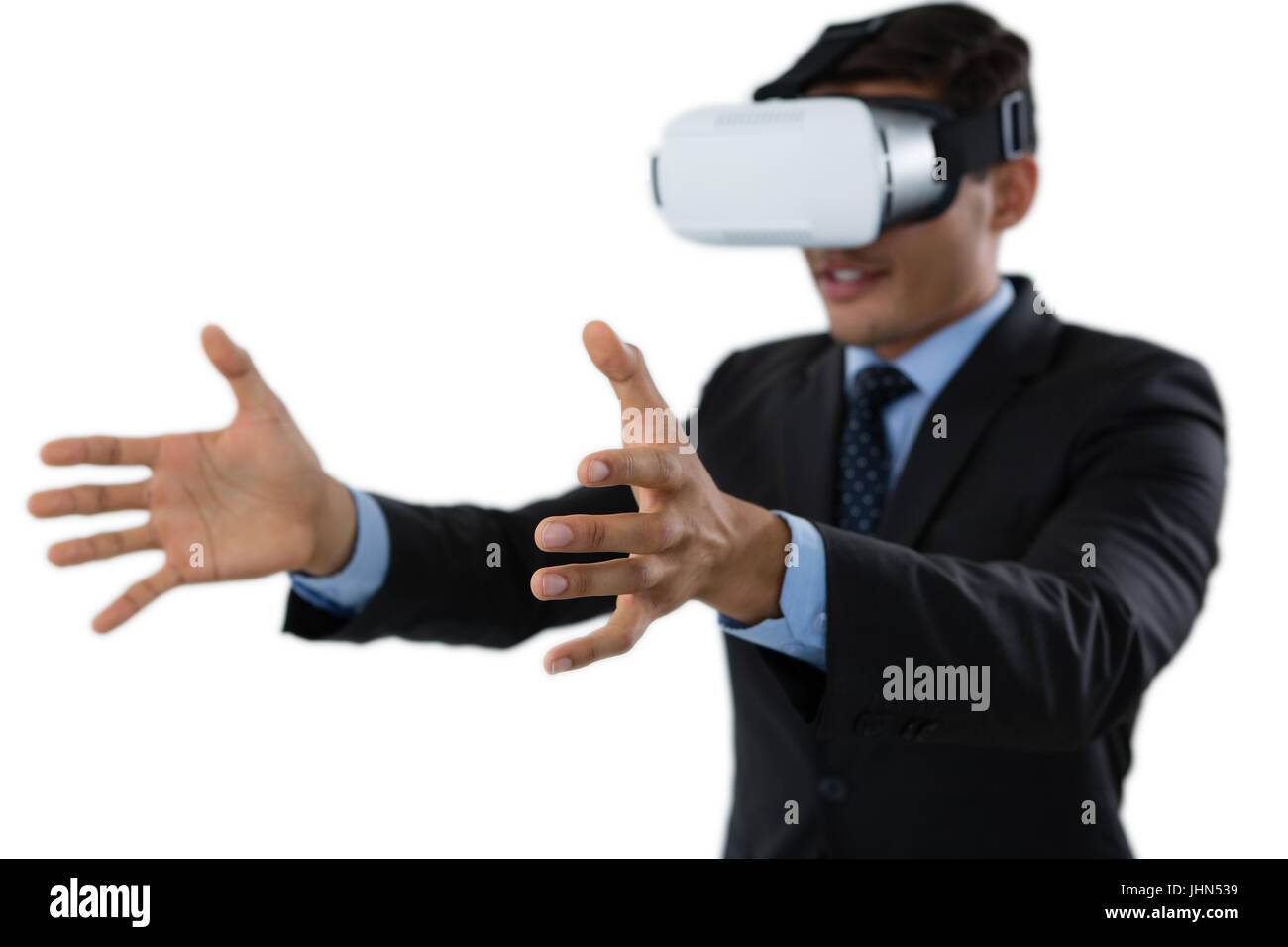 Smiling businessman gesturing while using vr glasses against white background Stock Photo