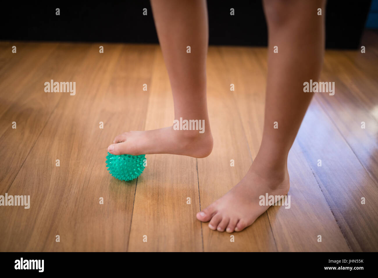 Low section of boy standing while stepping on stress ball at hospital ward Stock Photo
