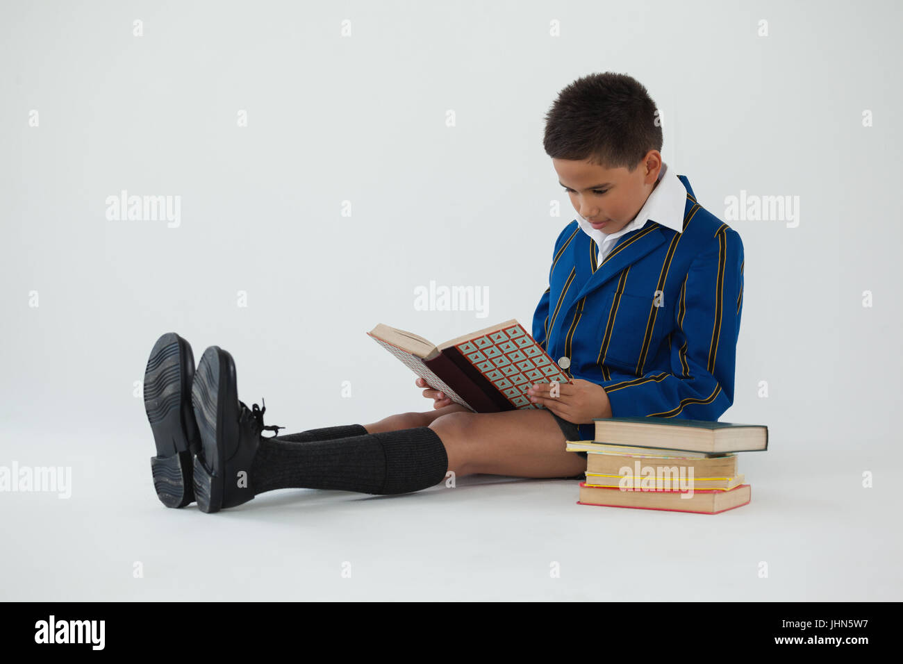 Attentive schoolboy reading book on white background Stock Photo - Alamy
