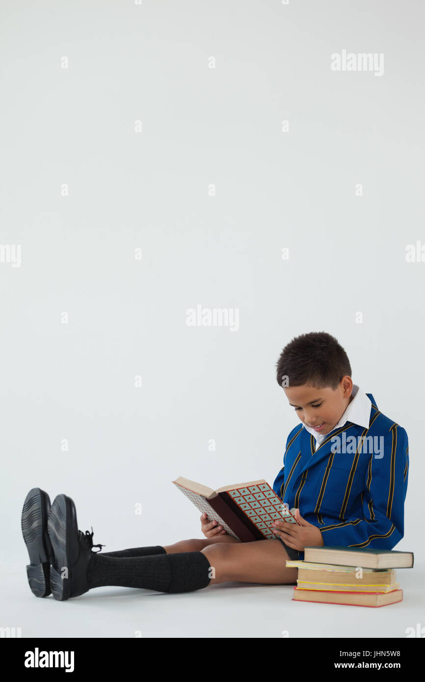 Attentive schoolboy reading book on white background Stock Photo - Alamy