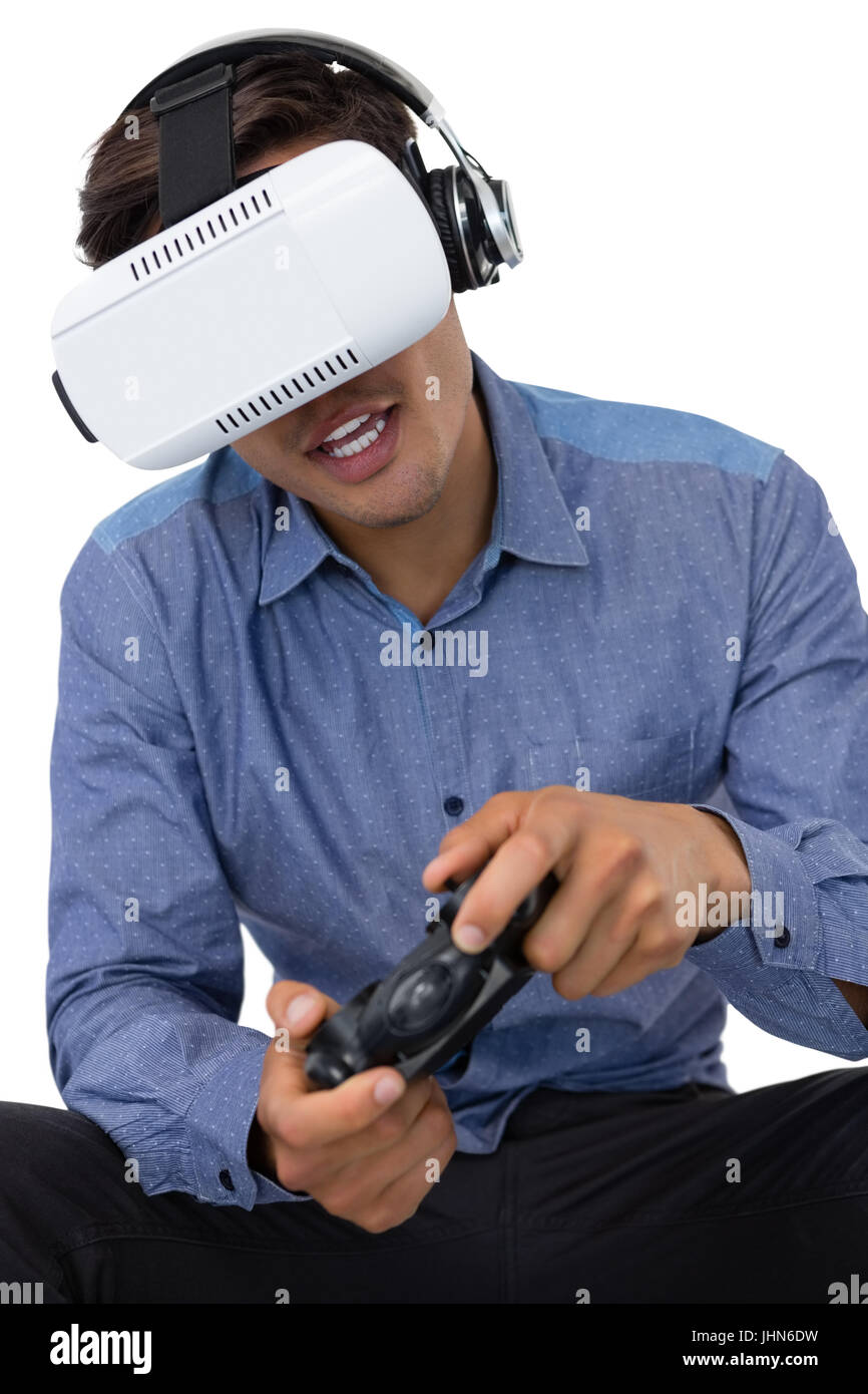 Young businessman using vr glasses while playing video game against white background Stock Photo