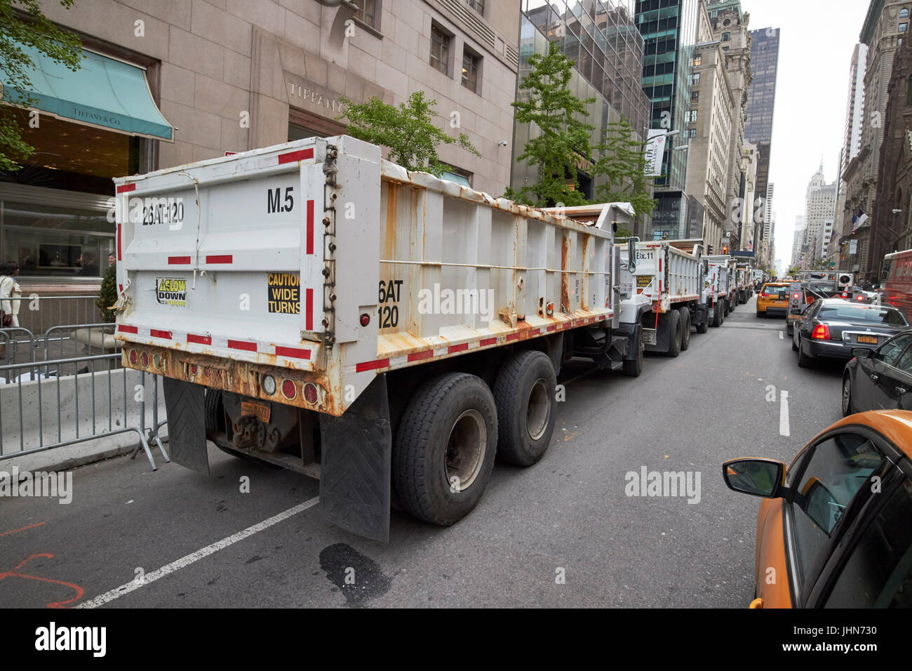 line of construction trucks filled with sand as defences outside trump tower on fifth avenue midtown New York City USA Stock Photo