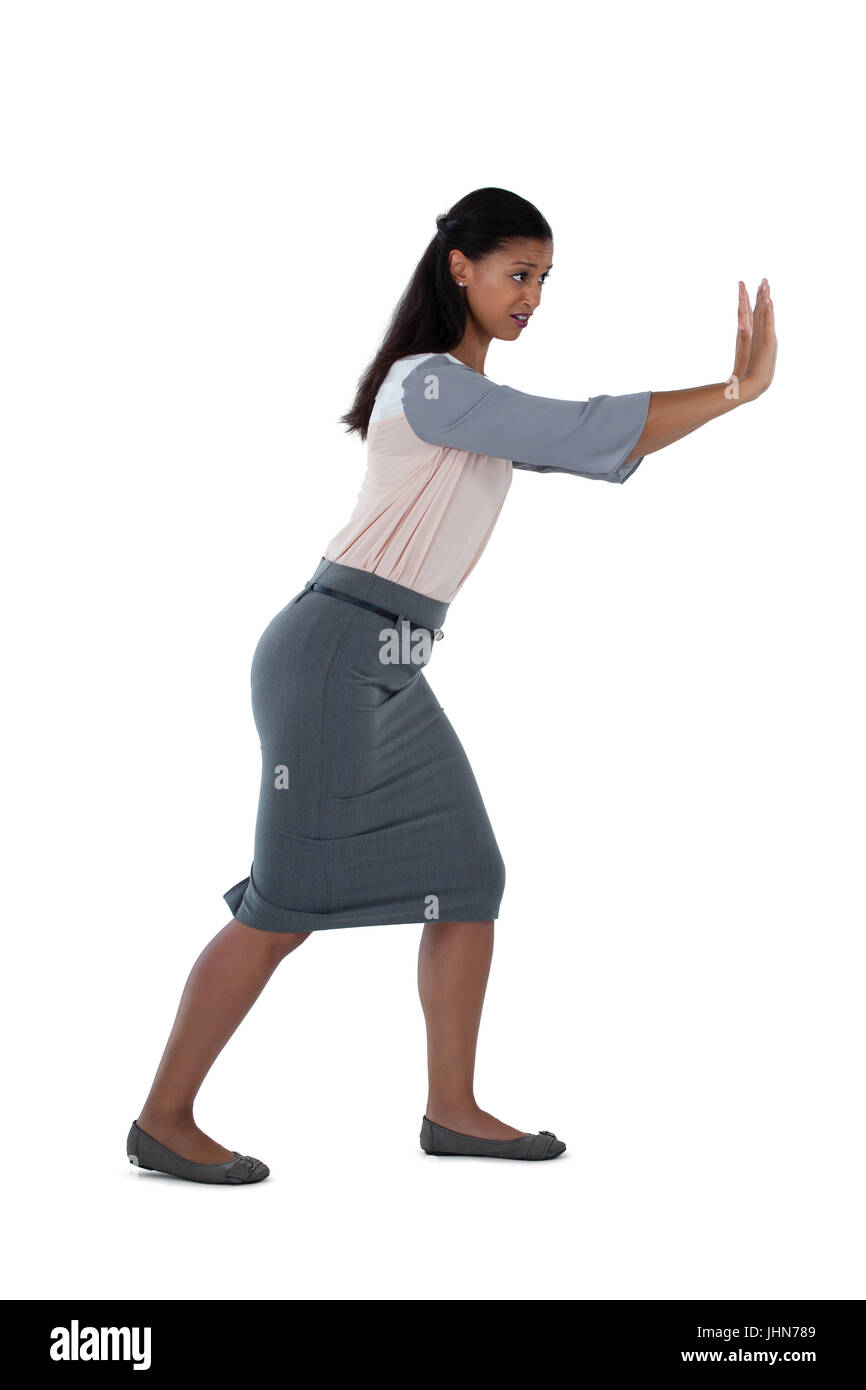 Side view of businesswoman pushing against white background Stock Photo