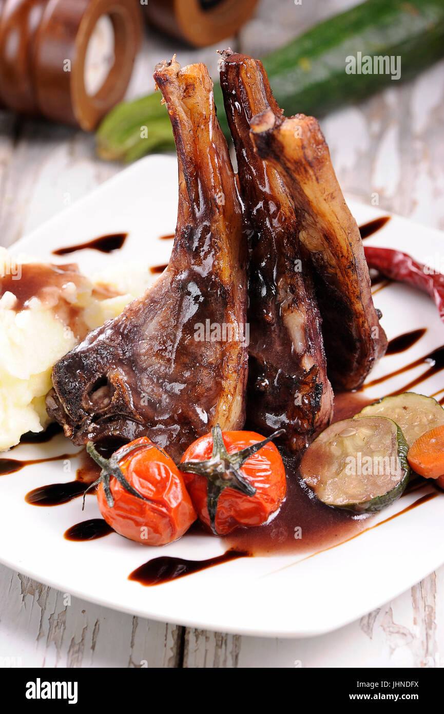 Roast lamb shank with roasted potatoes and carrots styled in a rustic setting Stock Photo