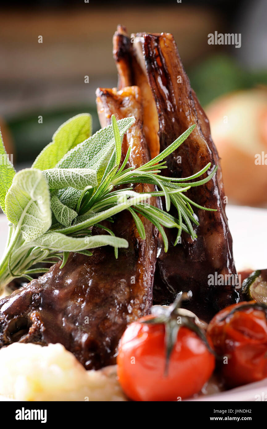 Roast lamb shank with roasted potatoes and carrots styled in a rustic setting Stock Photo