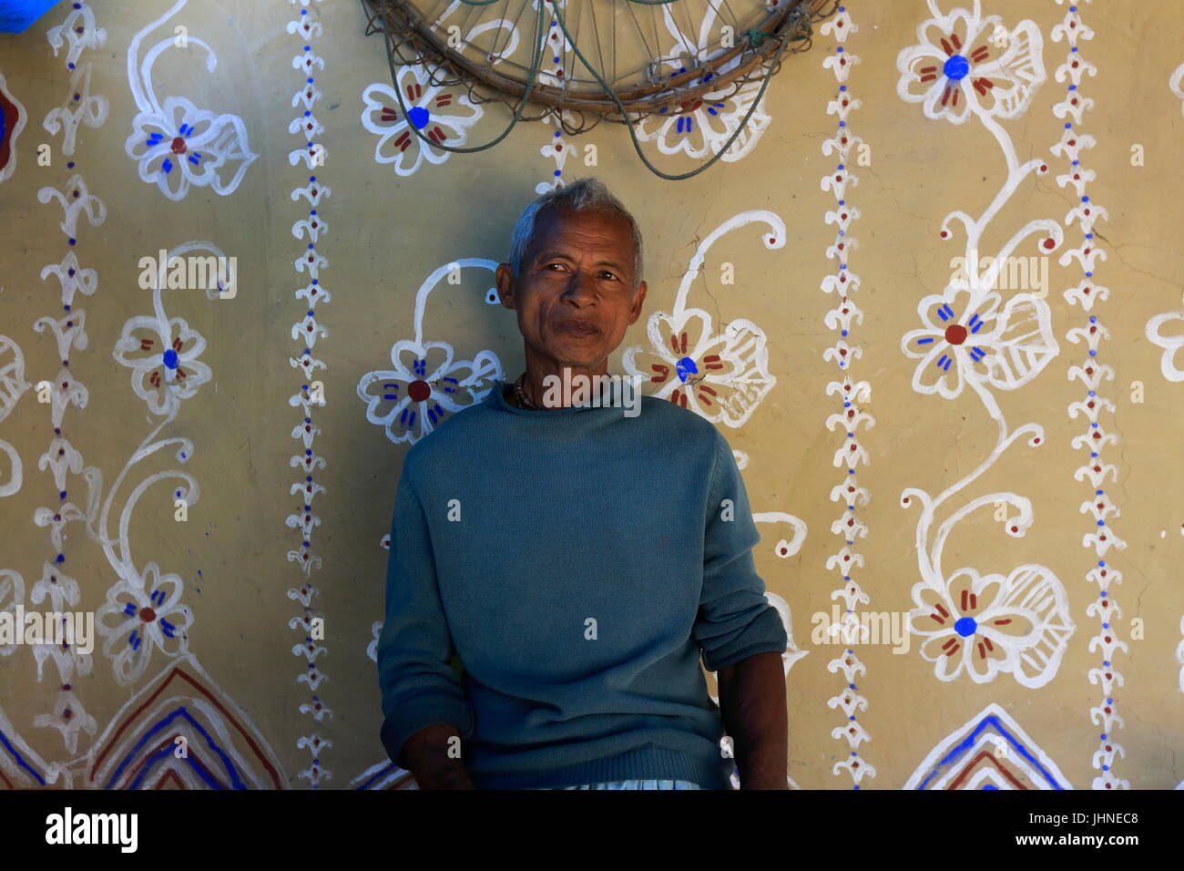A man sits in front of a traditional wall painting at a house at Tikoil village in Nachole upazila of Chapainawabganj district of Bangladesh. More tha Stock Photo