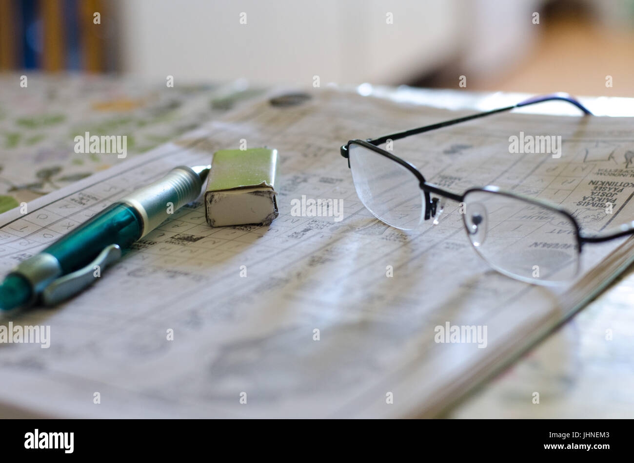 Pen and eraser on crosswordpuzzle beside a pair of glasses with light Pen and eraser on crosswordpuzzle beside a pair of glasses with light