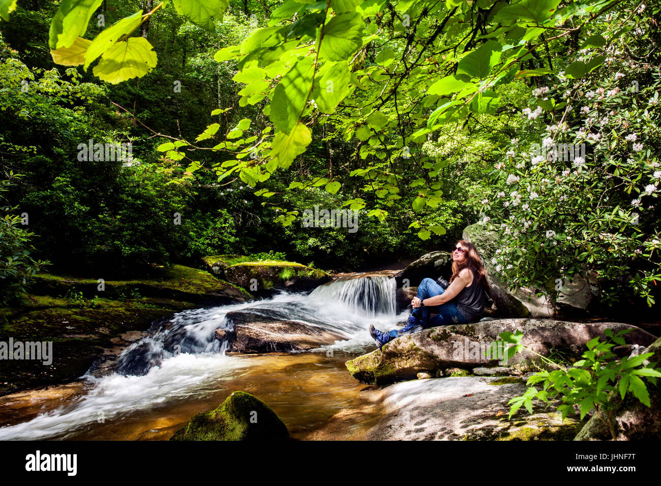 Young woman sitting by Davidson River in Pisgah National Forest - near Brevard, North Carolina, USA Stock Photo