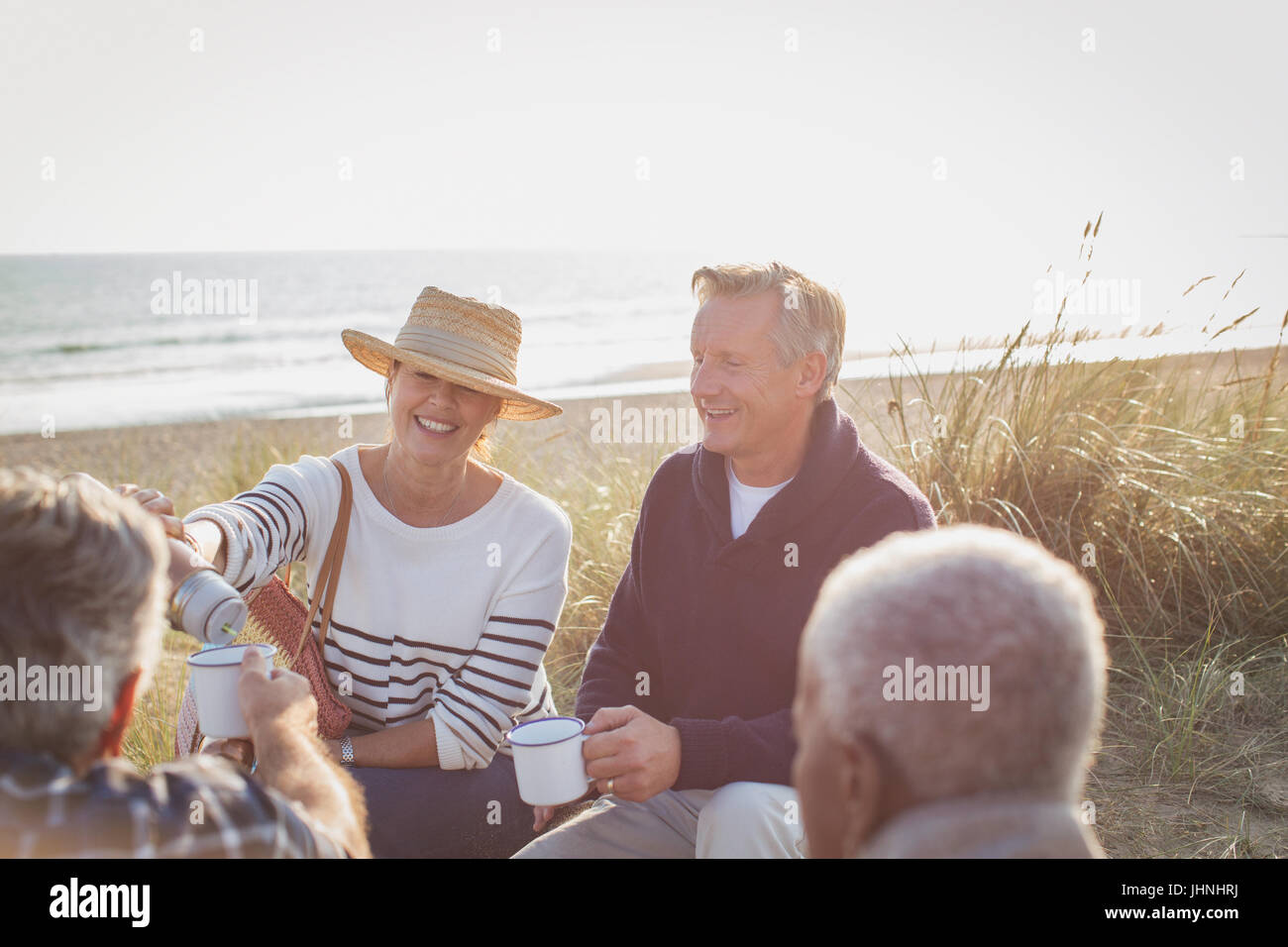 Senior couples drinking coffee on sunny beach Stock Photo