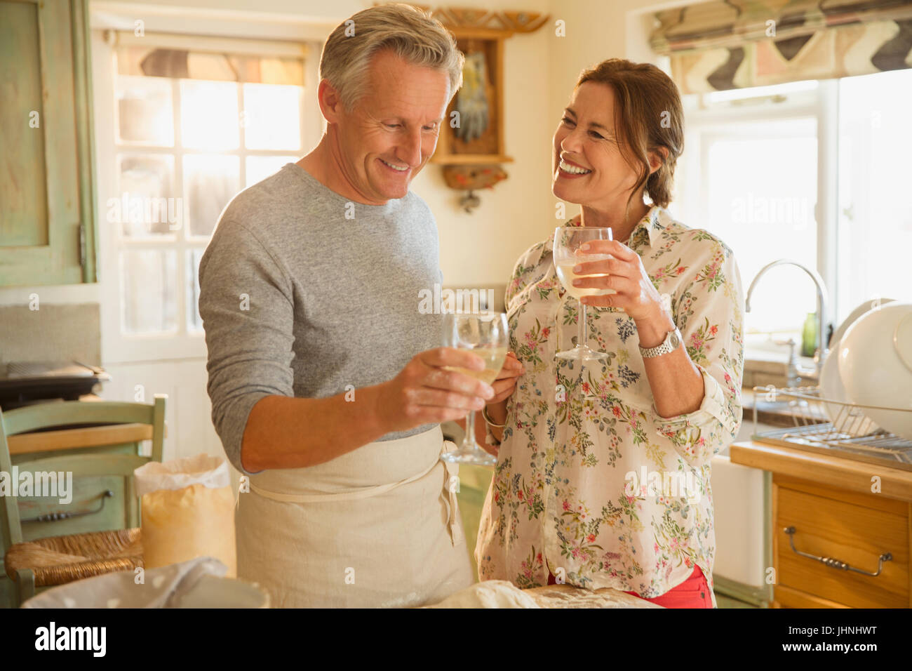 Smiling mature couple drinking wine and cooking in kitchen Stock Photo