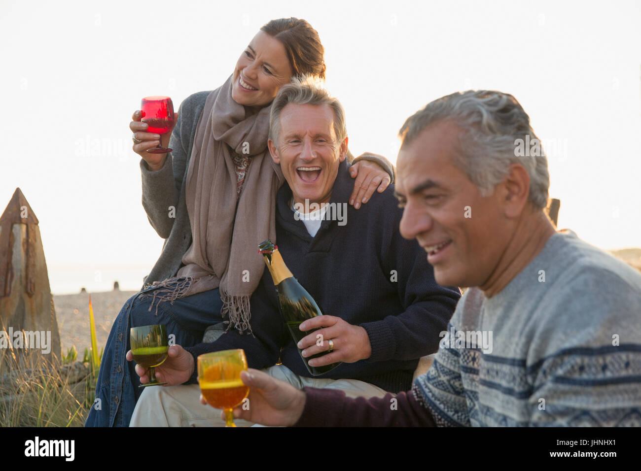 Playful mature friends drinking champagne on beach Stock Photo