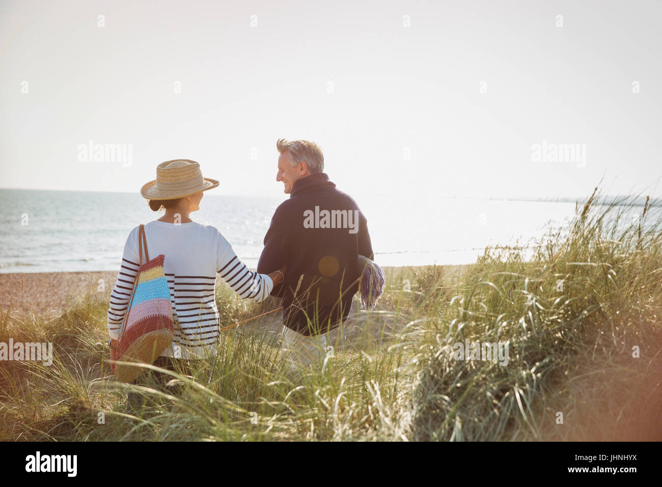 Mature couple walking arm in arm on sunny beach Stock Photo