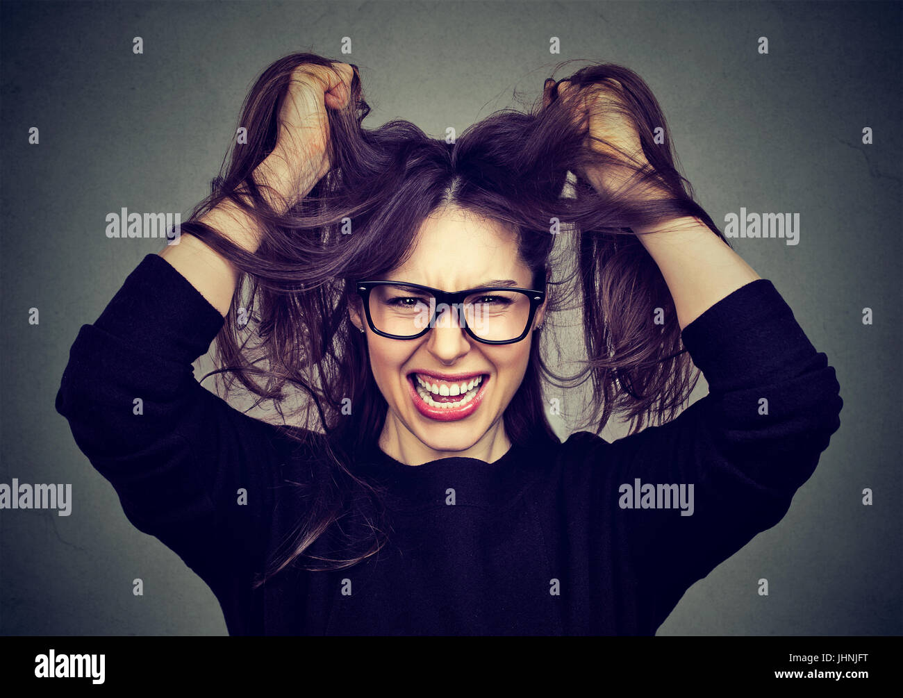 Closeup portrait stressed angry woman pulling hair out screaming Stock