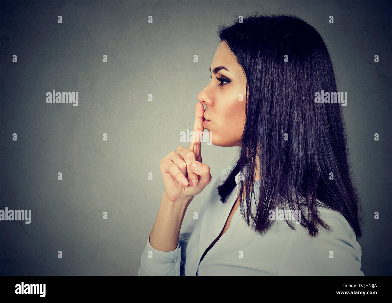 Businesswoman making silent sign with finger on lips. Stock Photo