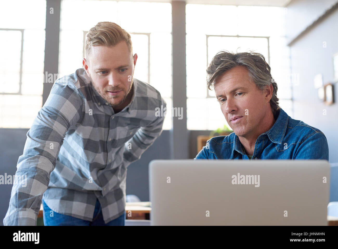 Focused young businessmen using a laptop at an office desk Stock Photo