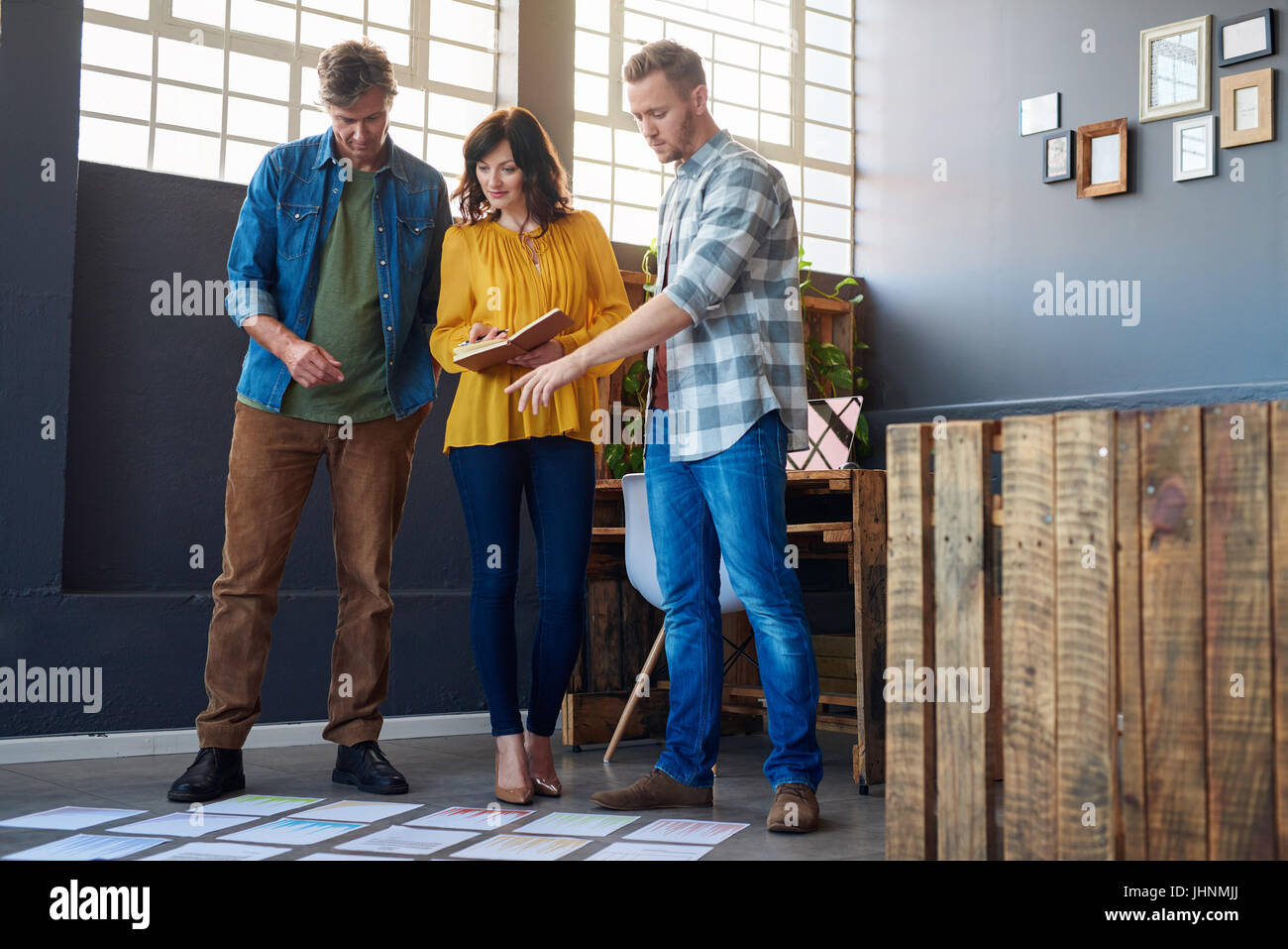 Colleagues talking together over papers lying on an office floor Stock Photo