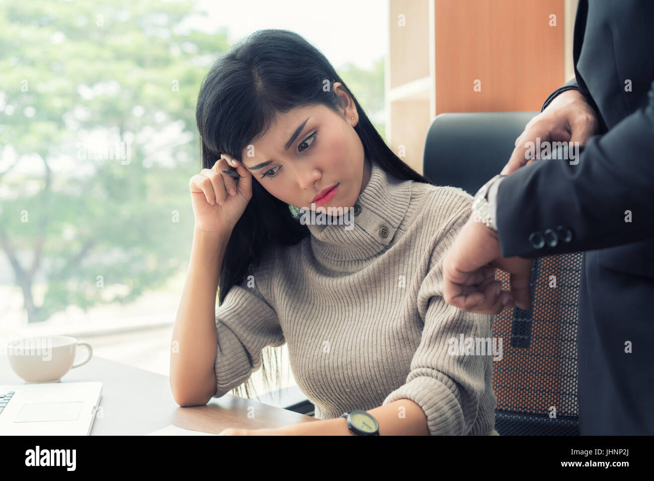 Angry business manager pointing his watch to subordinate businesswoman working missed deadline. Boss and worker at work having conflict. Stock Photo