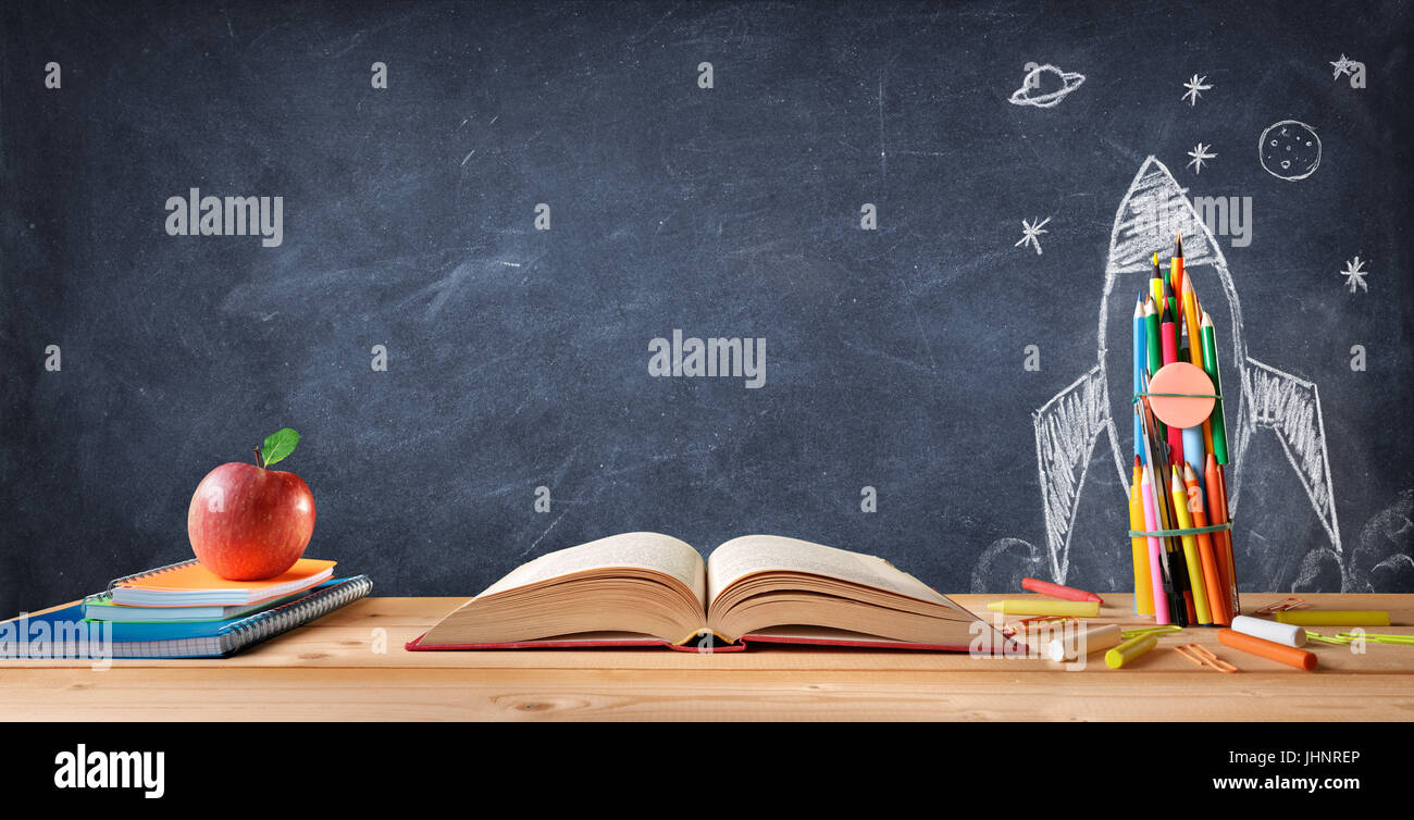 Start School Concept - Supplies On Desk And Rocket Drawn On Blackboard Stock Photo