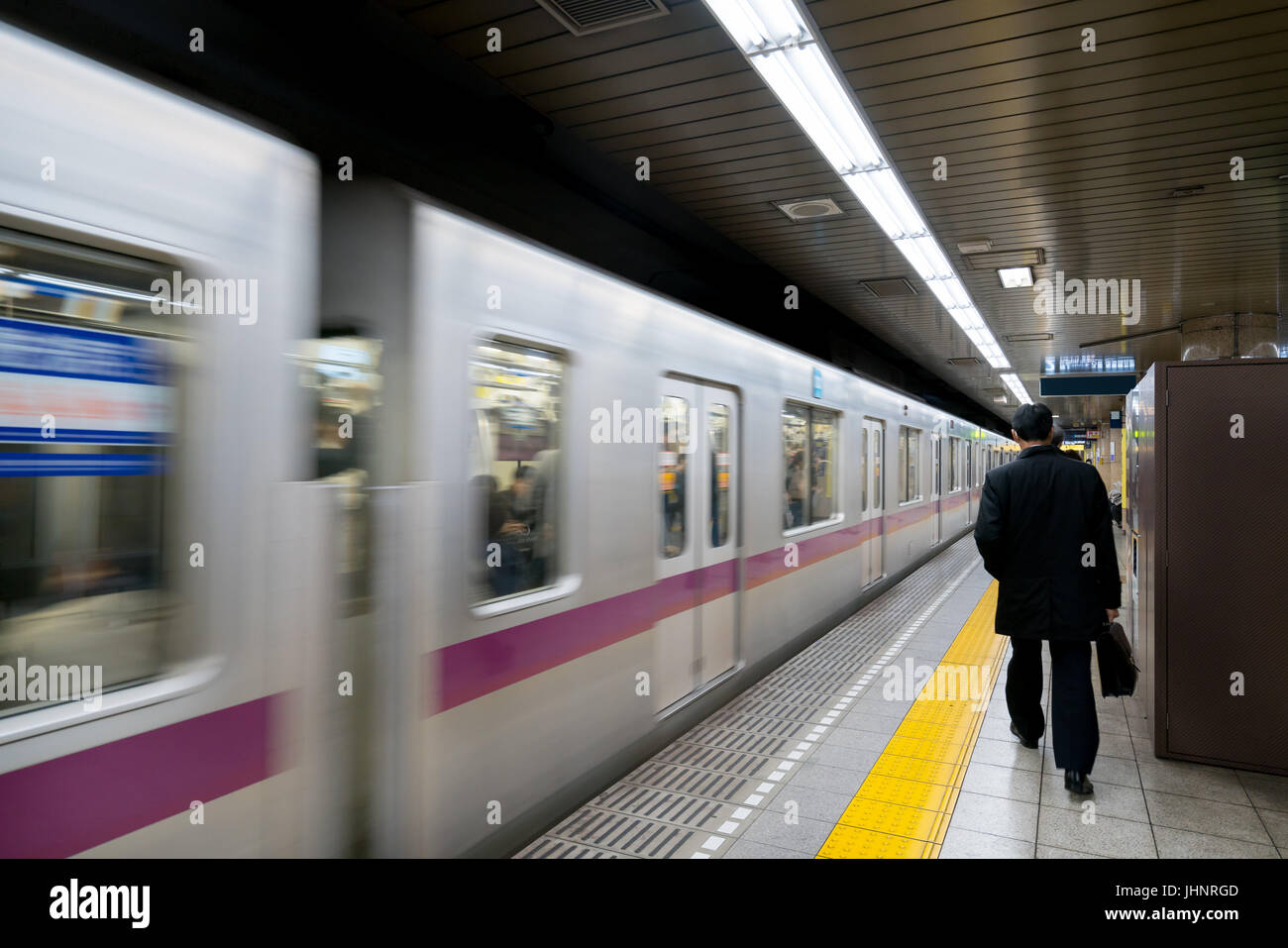 Interior of a Tokyo subway station and platform with subway commuters in Tokyo, Japan. Stock Photo