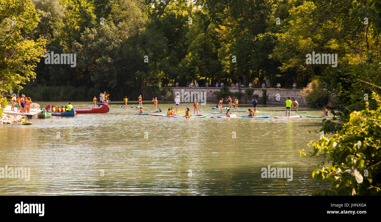 Children learning  paddle boarding  on the River Tagus / Tajo as it flows through the royal gardens in Aranjuez in the Madrid province of Spain Stock Photo