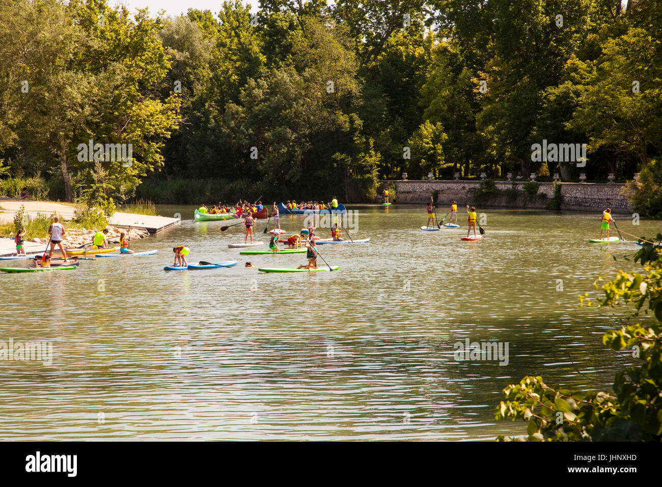 Children learning  paddle boarding  on the River Tagus / Tajo as it flows through the royal gardens in Aranjuez in the Madrid province of Spain Stock Photo