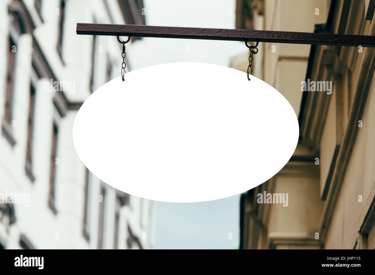 Blank Oval Signage hanging from wrought iron bracket, in the city Stock Photo