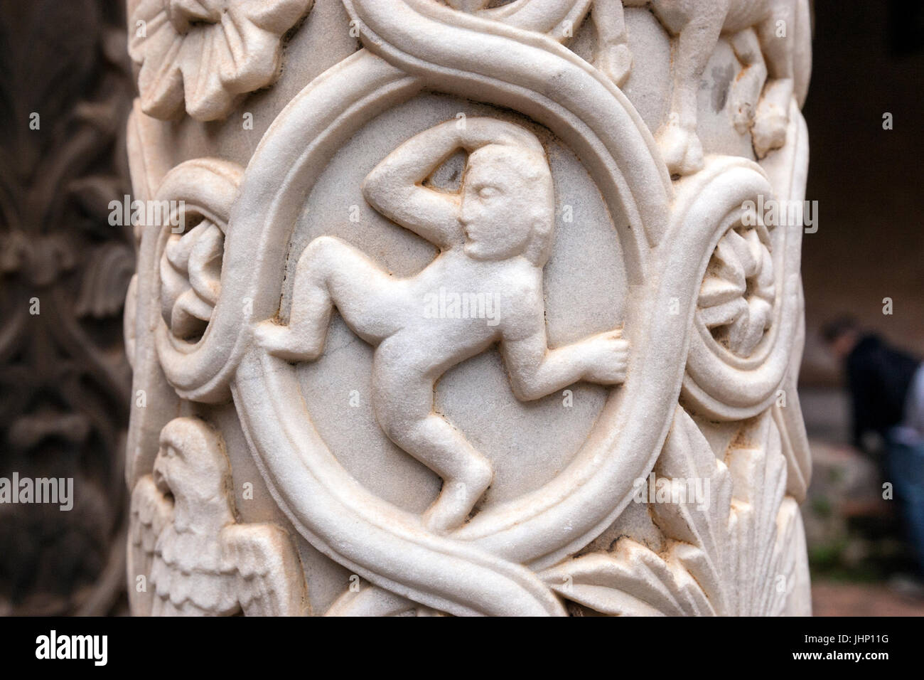 Monreale cathedral cloister carved column shaped like stylized palm stems, with figures standing, relief leaves. Stock Photo