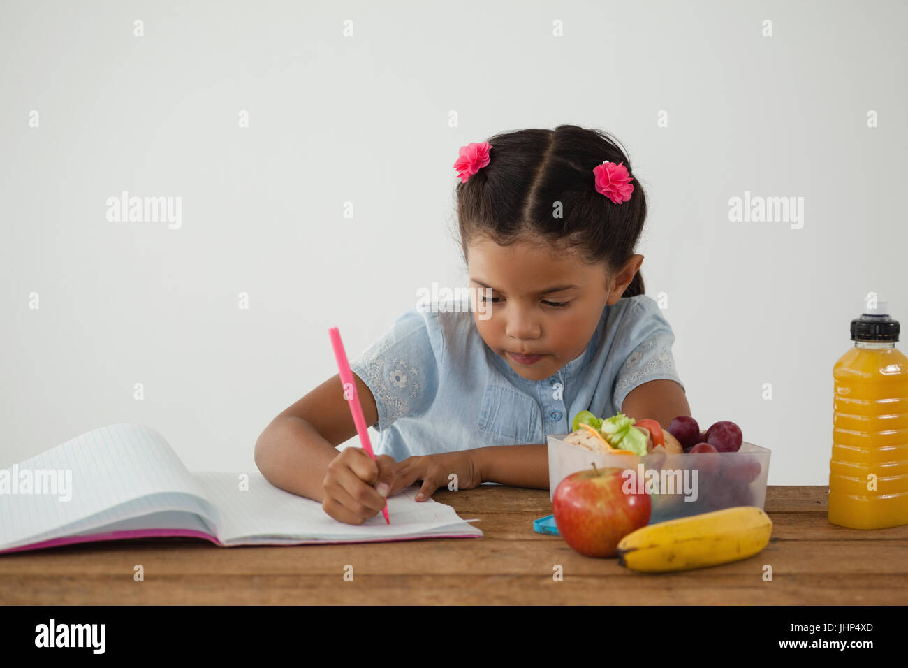 Attentive Schoolgirl Doing Her Homework Against White Background Stock
