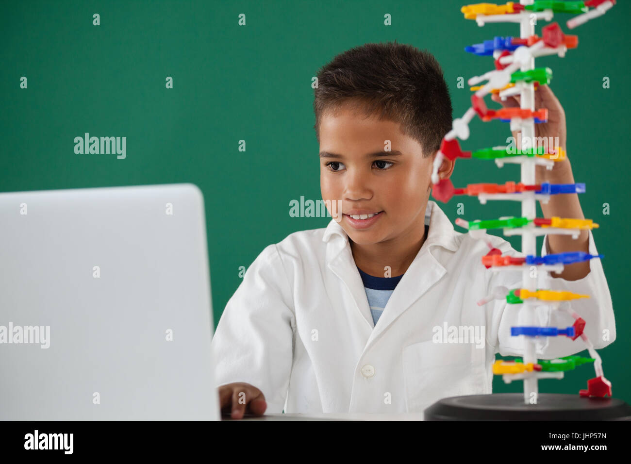 Smiling schoolboy experimenting molecule model in laboratory at school ...
