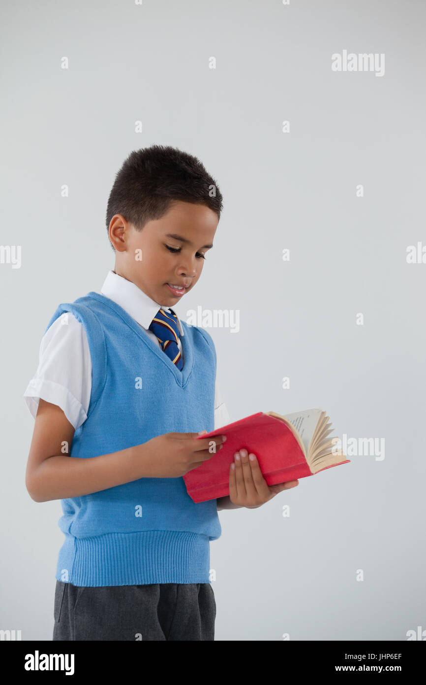 Attentive schoolboy reading book against white background Stock Photo ...