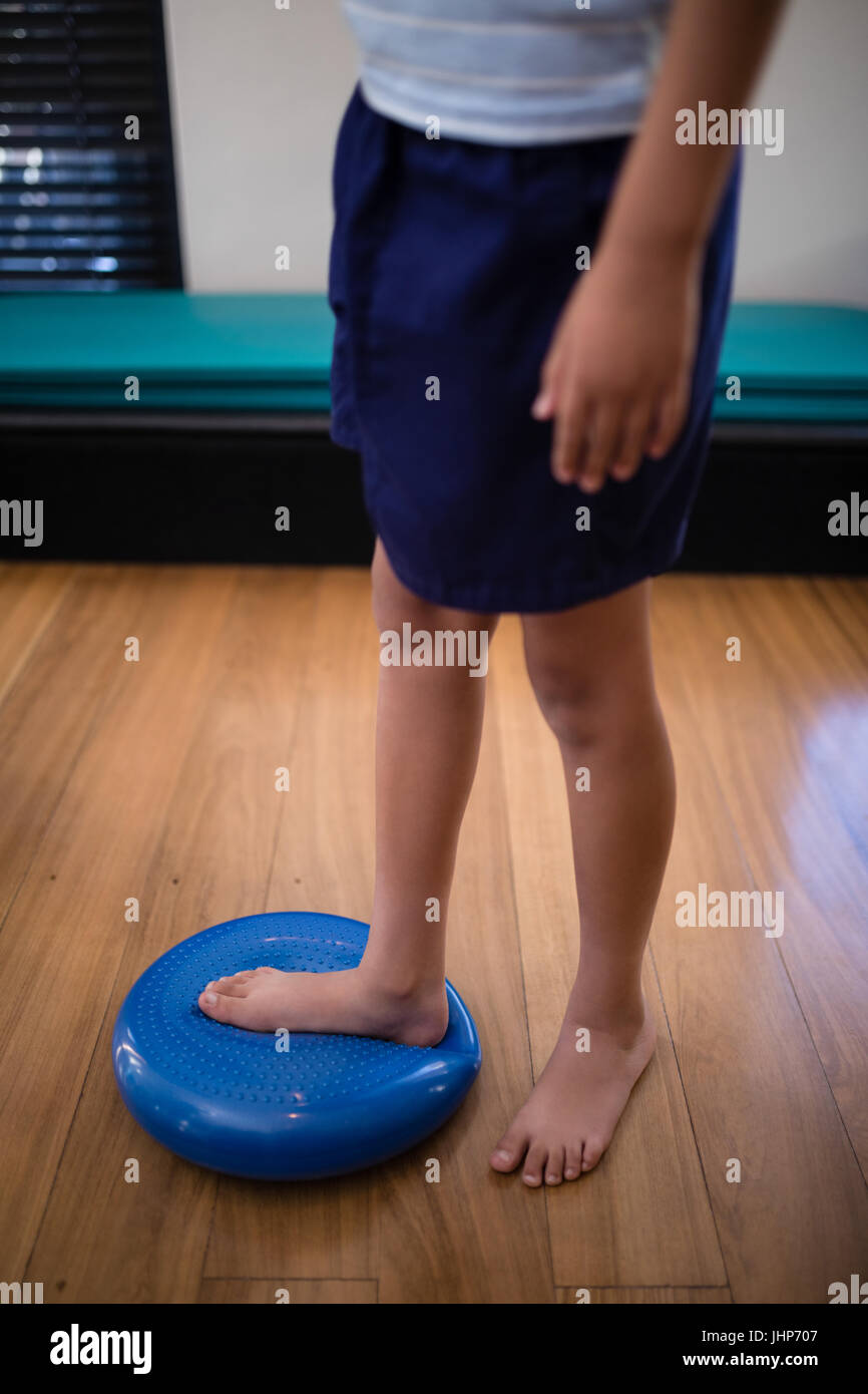 Low section of boy standing on large blue stress ball at hospital ward Stock Photo