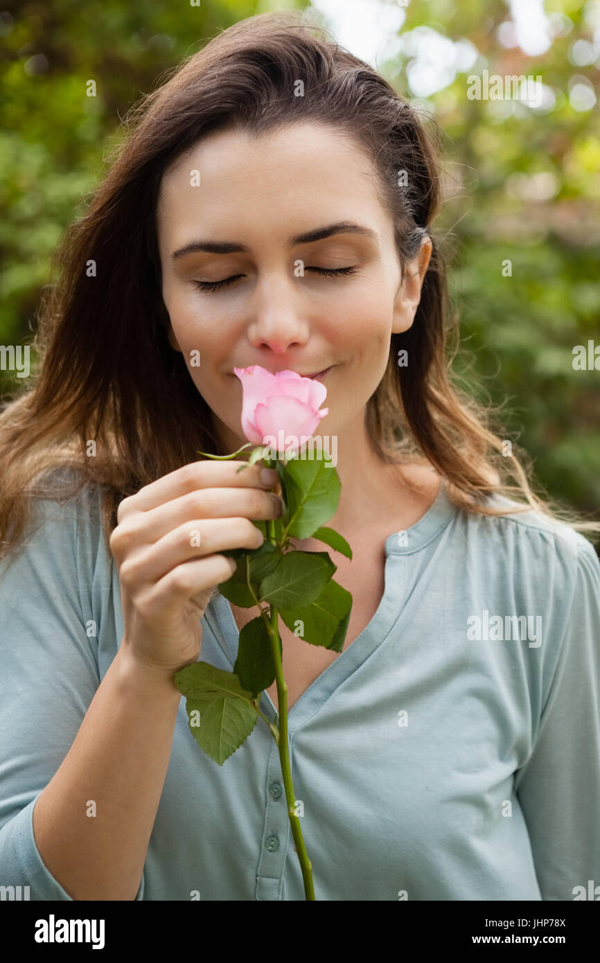 Beautiful woman with eyes closed smelling pink rose at garden Stock Photo