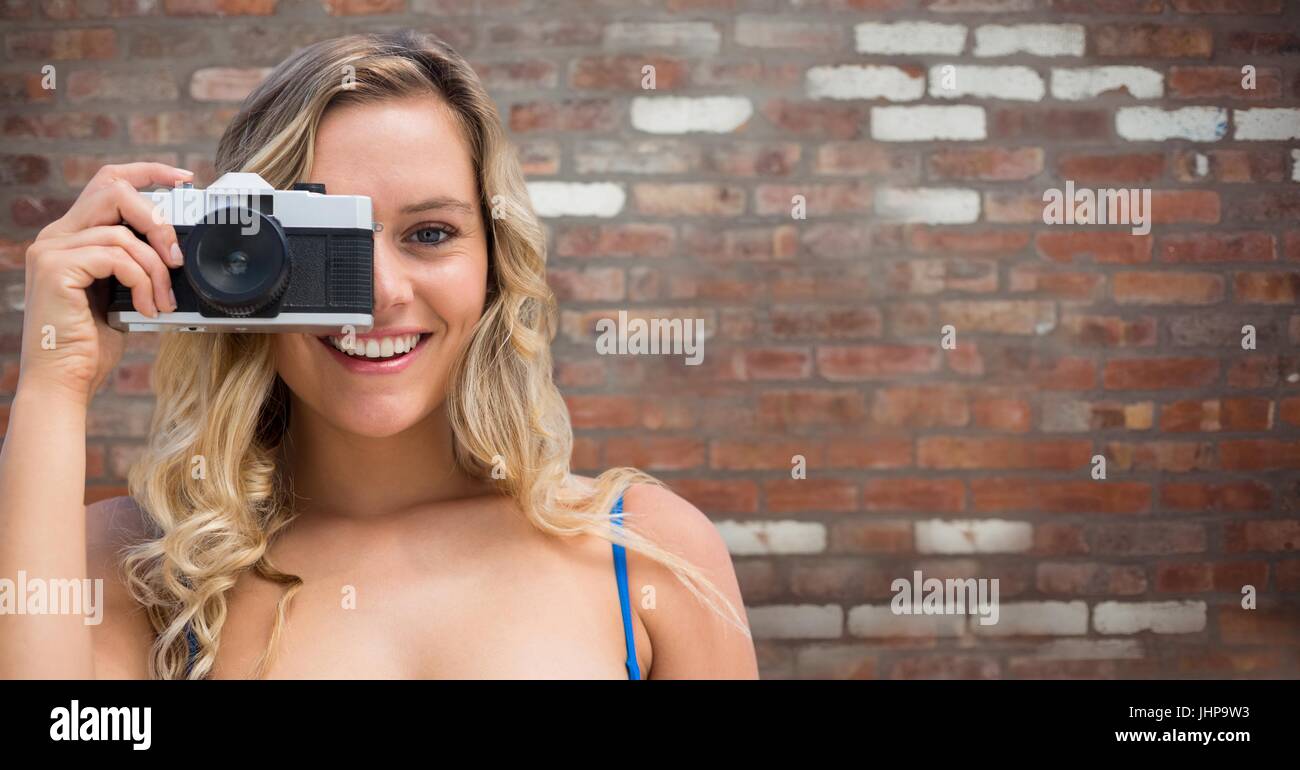 Digital composite of Close up of millennial woman with camera against red brick wall Stock Photo