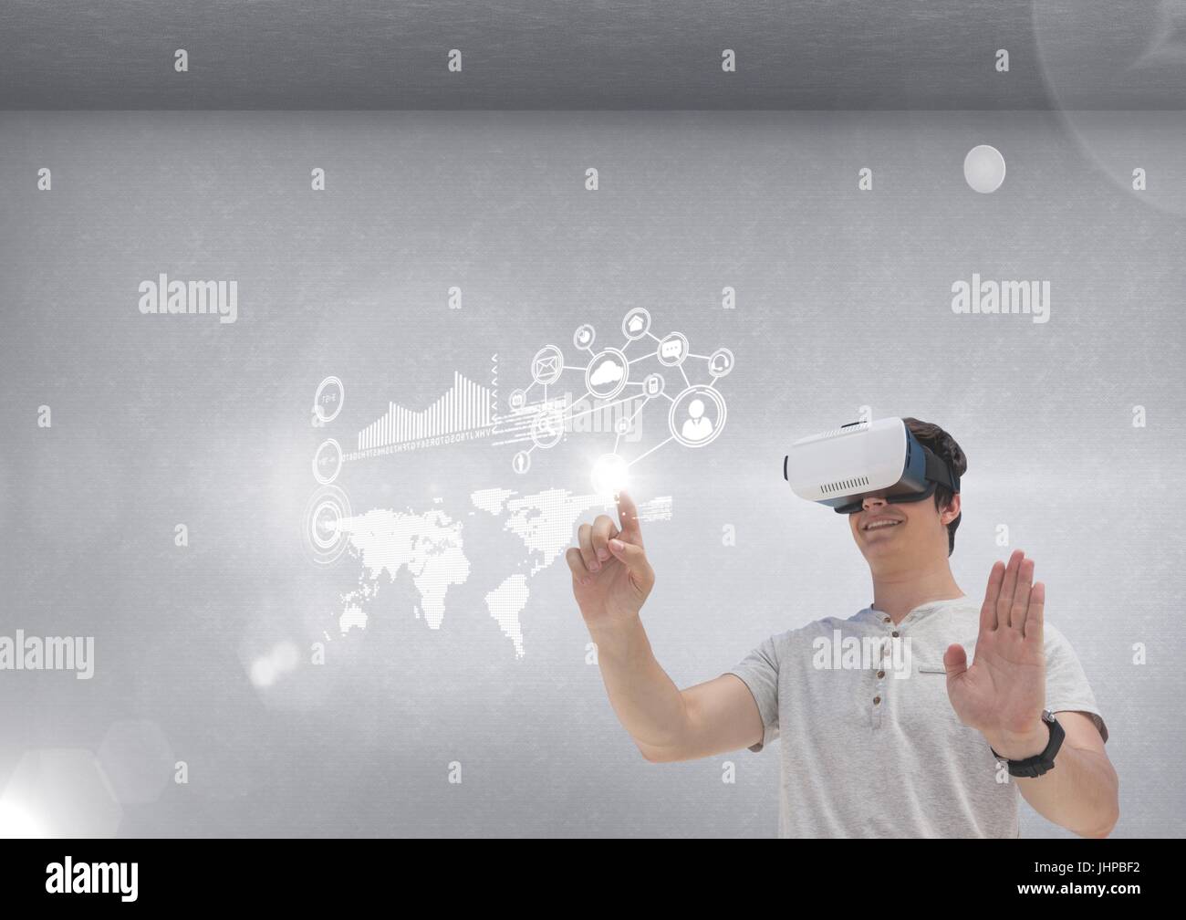Digital composite of Happy man in VR headset touching interface against grey background with flares Stock Photo