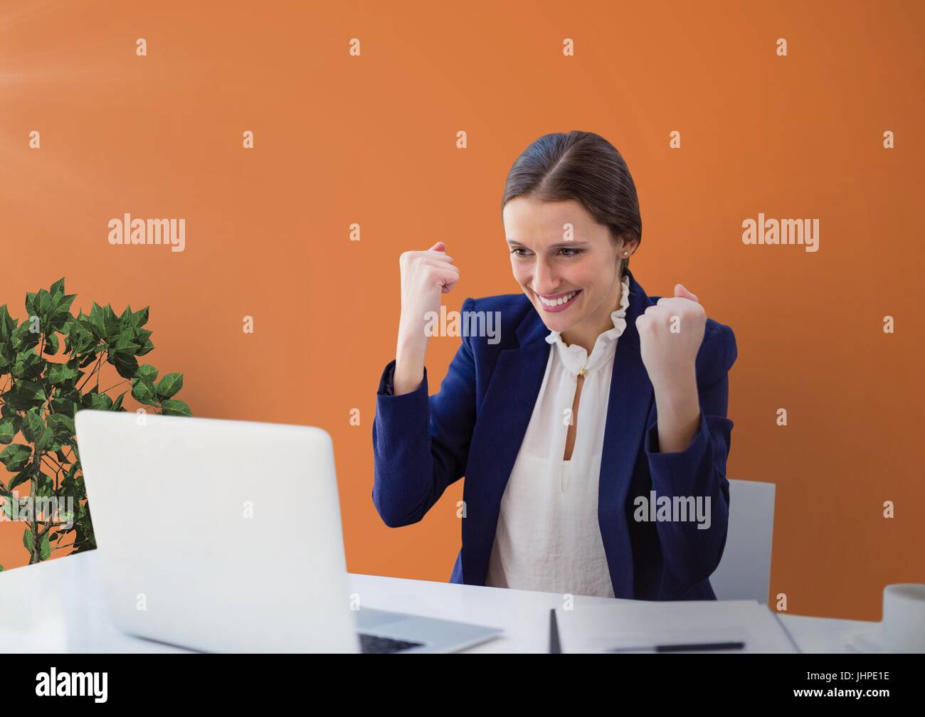 Digital composite of Excited business woman at a desk looking at a ...