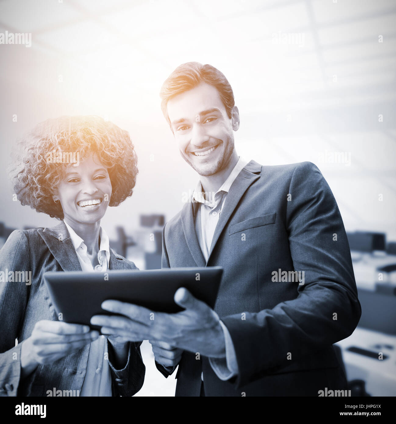 Business people standing with a tablet against computers in office Stock Photo