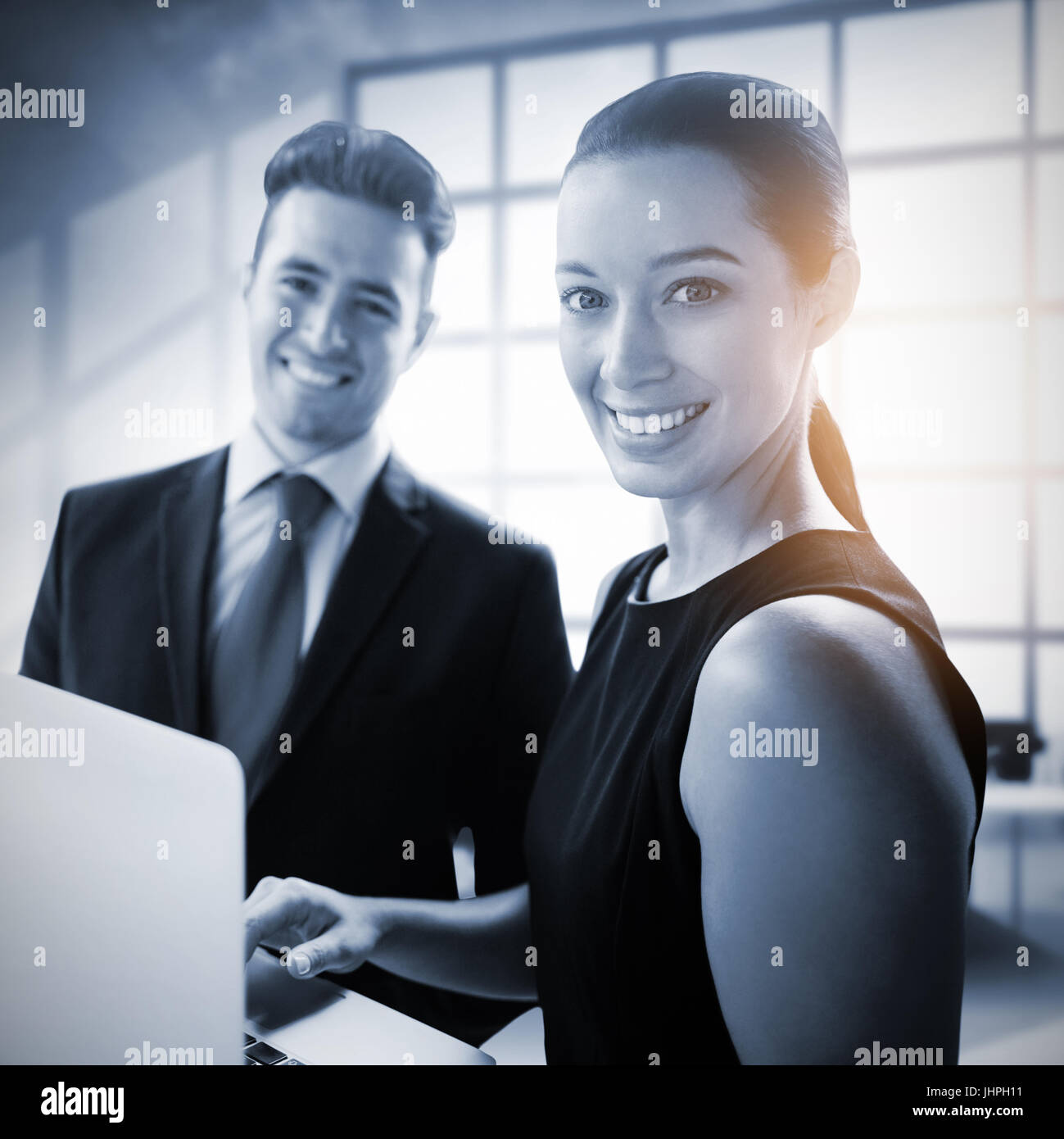 Business people standing with a laptop against interior of empty office Stock Photo