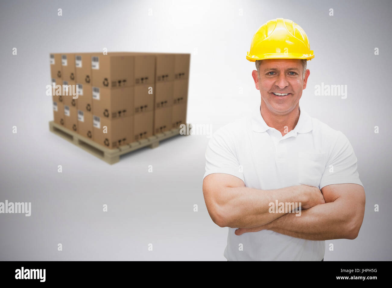 Worker wearing hard hat in warehouse against grey background Stock