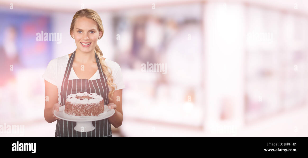 Portrait of young woman holding cake against modern reception desk Stock Photo