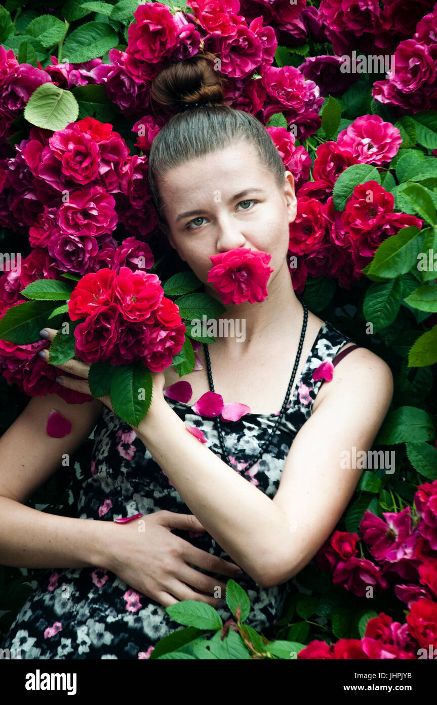 A portrait of a young woman near rose bush Stock Photo - Alamy