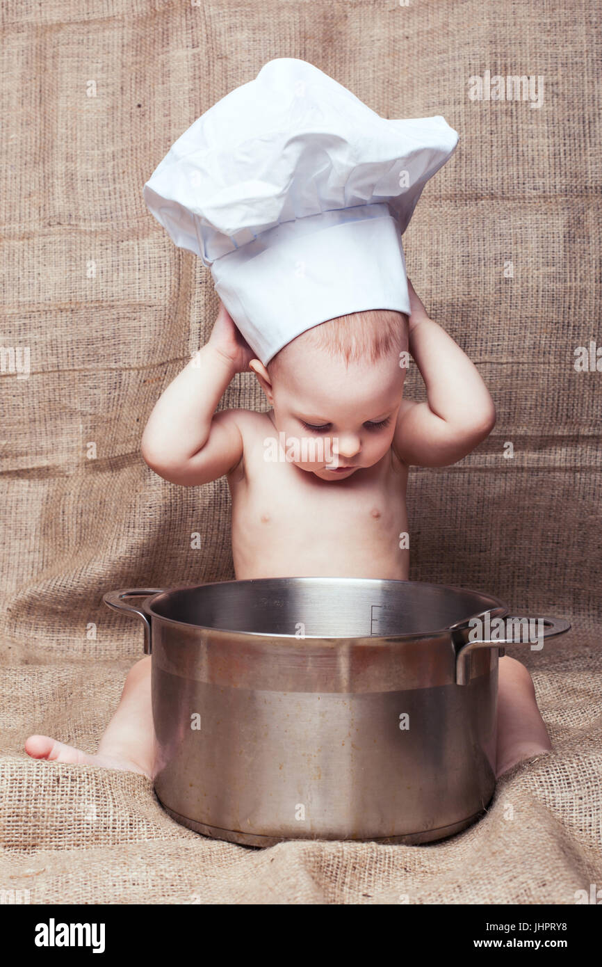 Child playing a chef. She wears a large kitchen hood Stock Photo