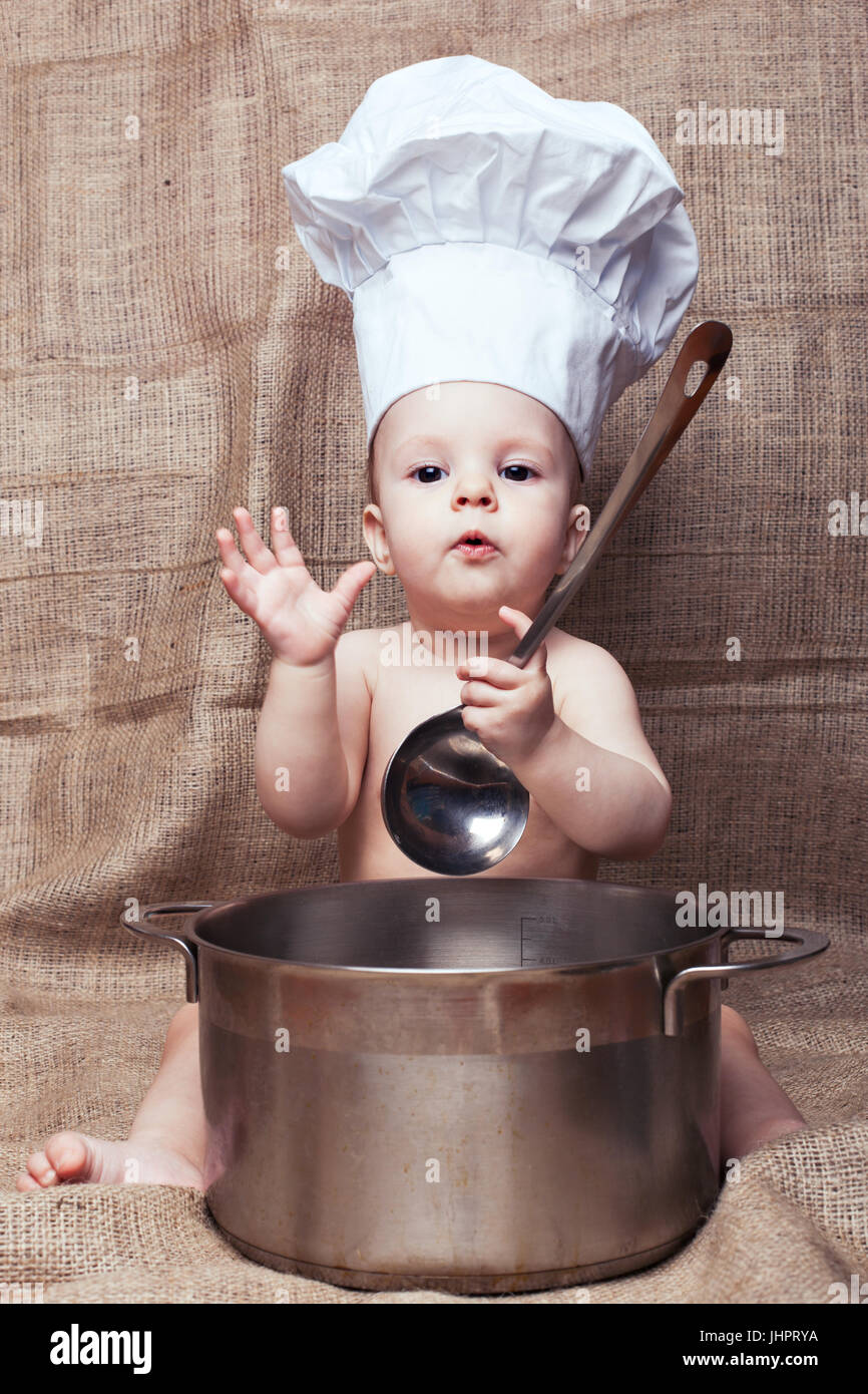 Little girl in a kitchen hood playing with pan and ladle Stock Photo