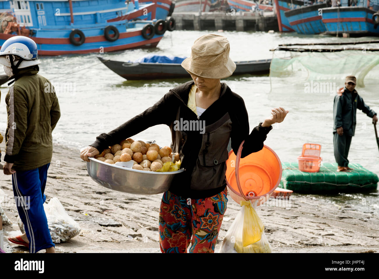 Vietnamese woman carrying a large bowl with deep fried sweet bread (Mantou). December 26, 2013 - Da Nang, Vietnam Stock Photo