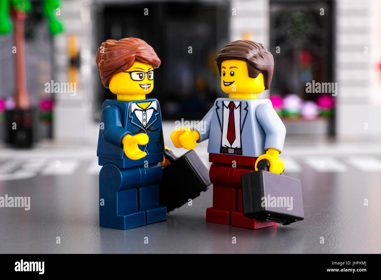 Tambov, Russian Federation - June 22, 2017 Lego businessman and businesswoman with suitcases meet on the street. Studio shot. Stock Photo