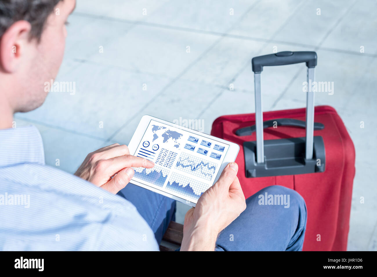 Businessman working with financial dashboard with charts and metrics or electronic banking app on a digital tablet computer at airport Stock Photo