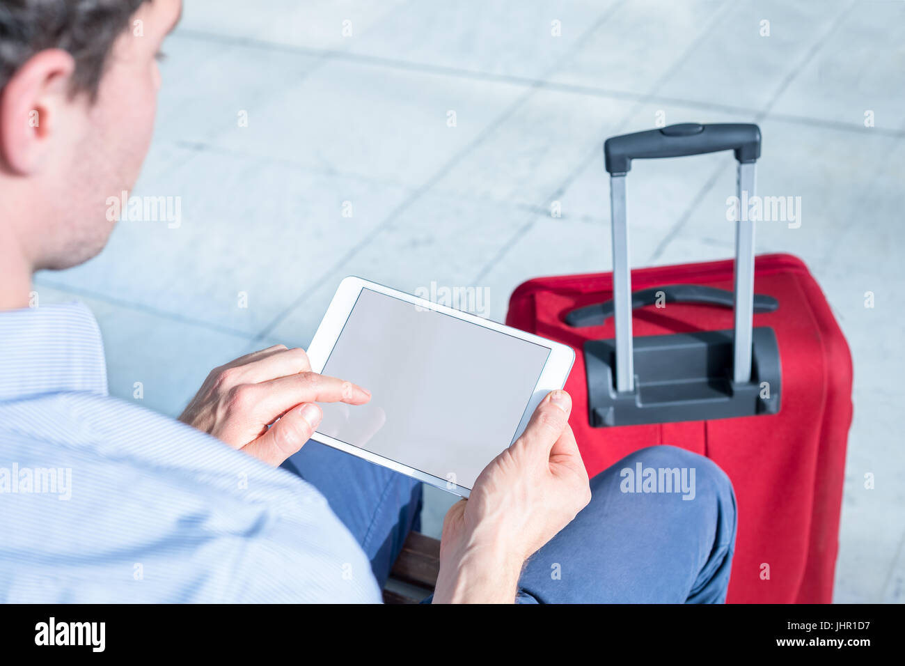 Person using a digital tablet computer with internet at airport and showing blank screen, business travel Stock Photo