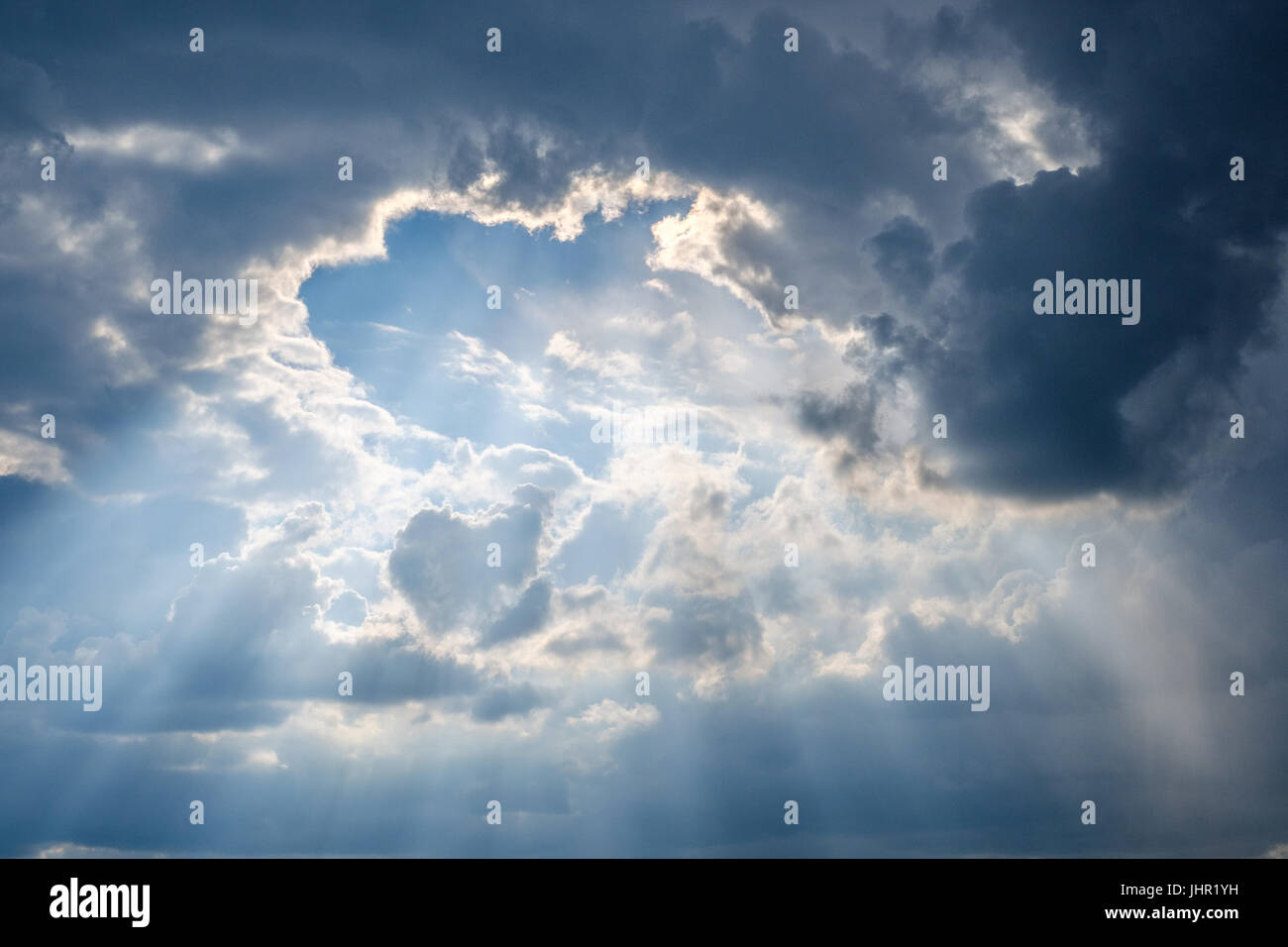 sun rays shining through thick cloudy sky - Stock Photo