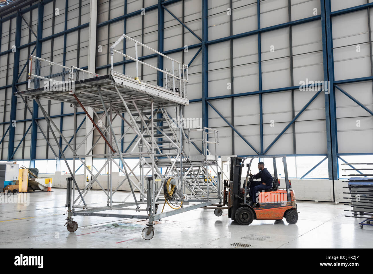 Aircraft maintenance engineer driving forklift truck at airlines maintenance facility Stock Photo